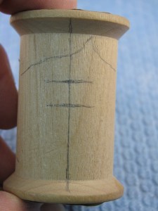 Draw a center line and add lines for the hair. The ends of the hair line just fade into and around the spool. Place the part in the hair to the side of the centerline to add interest. Notice I added a line for the eyes and the bottom of the nose.